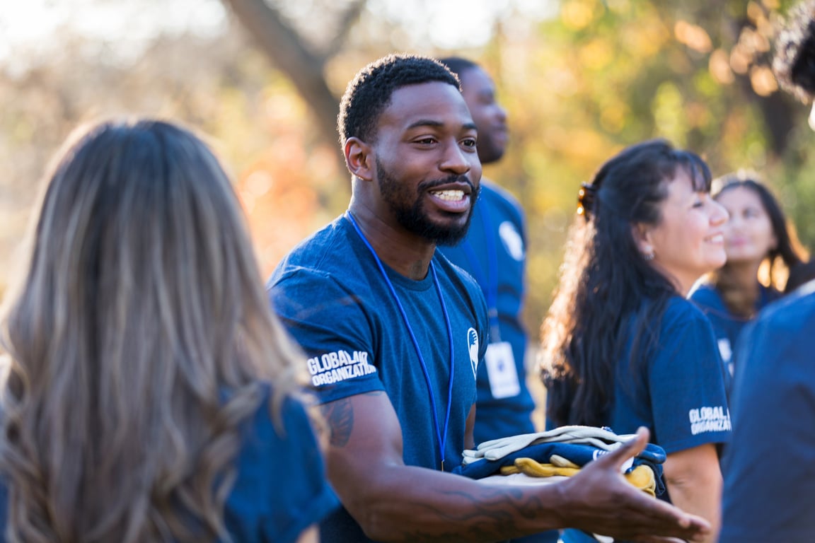 Charity event organizer greets volunteer during community cleanup event